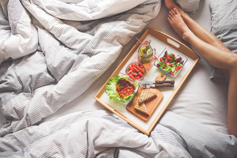 Breakfast board on the bed next to guest lying on the bed | bed and breakfast software