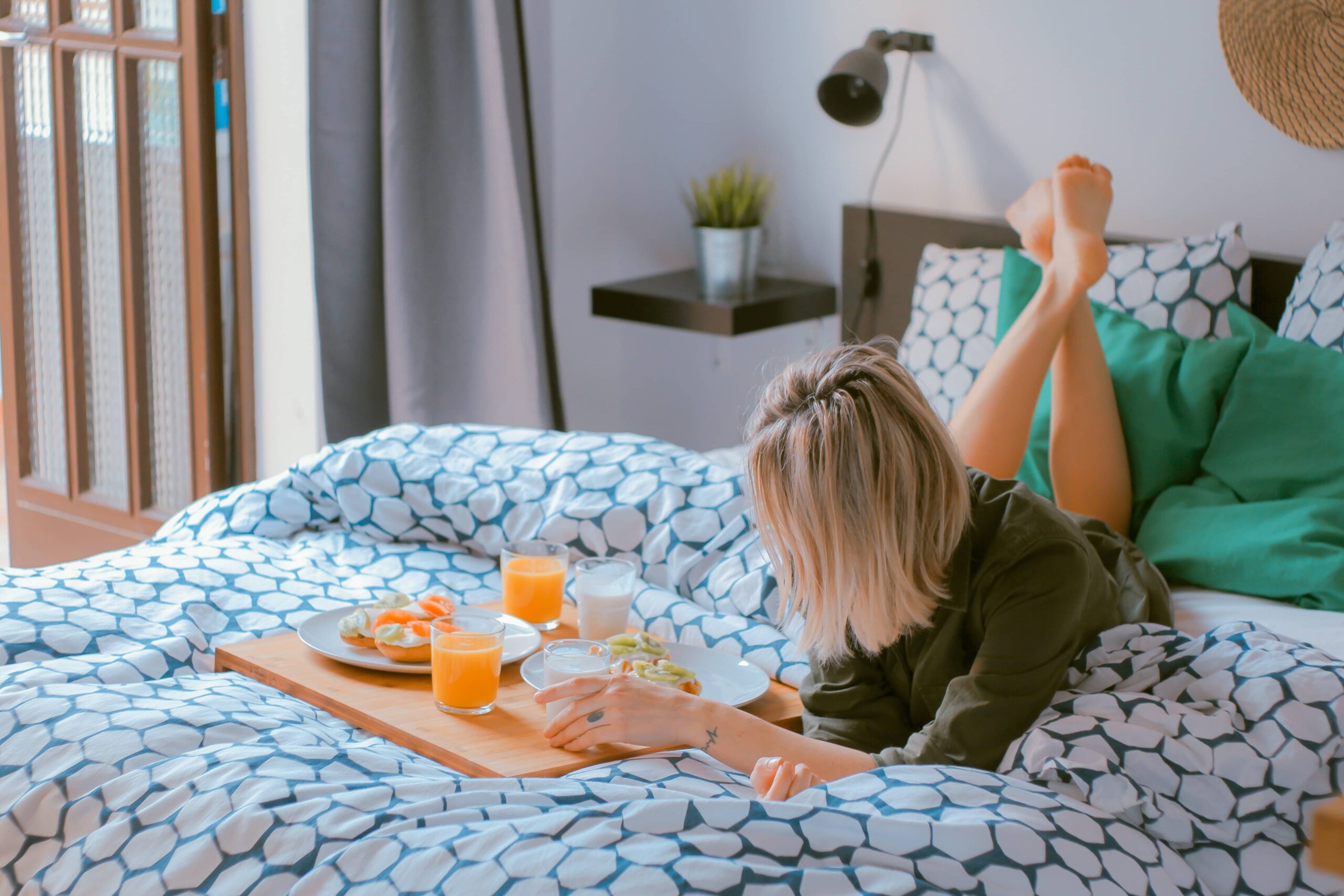 Woman lying on the bed with a breakfast board Bed and breakfast software